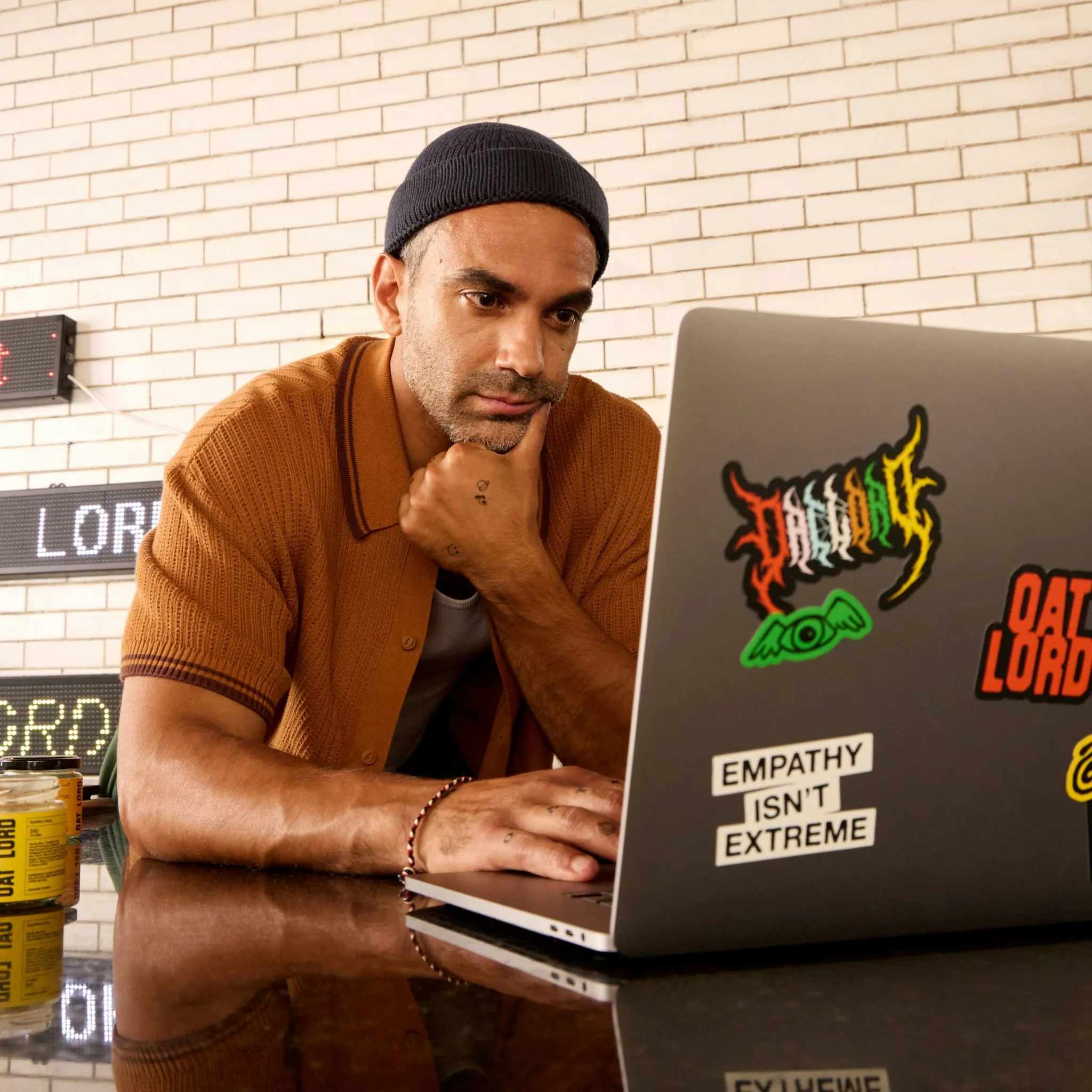 Man met muts werkt op een laptop